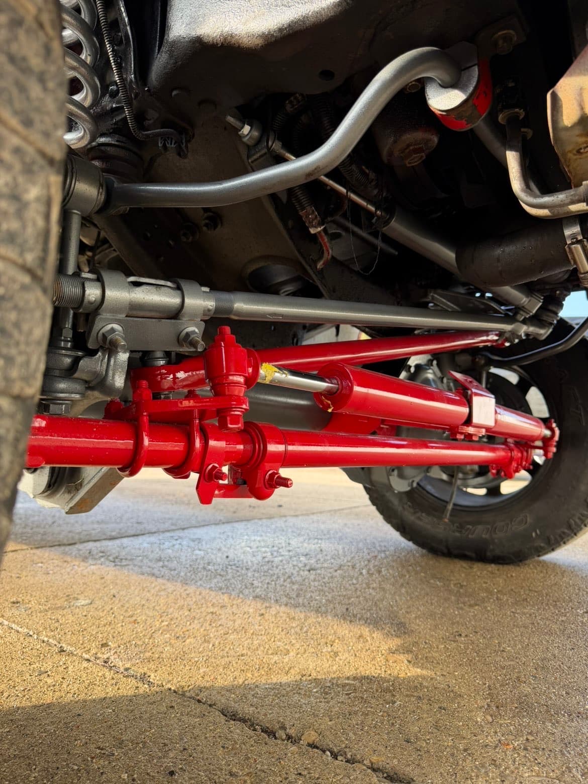 Red powder coated steering and radius arms installed under truck — TP Customs